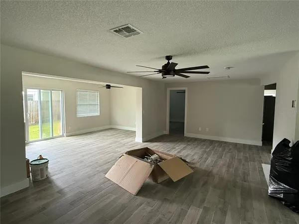 an empty room with wooden floor and ceiling fan