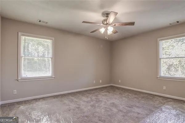 an empty room with windows and fan