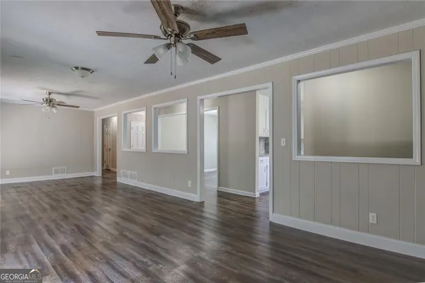 a view of an empty room with wooden floor and a ceiling fan