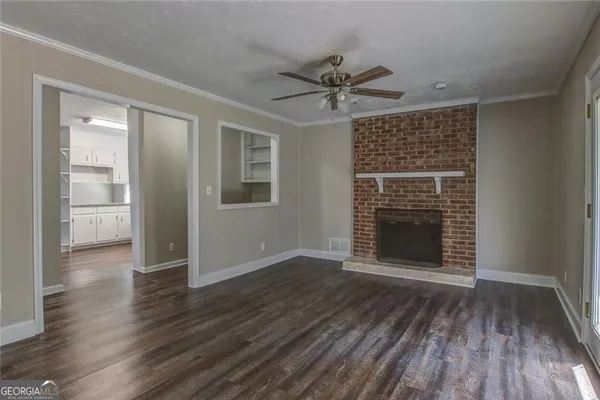 an empty room with wooden floor a ceiling fan and windows