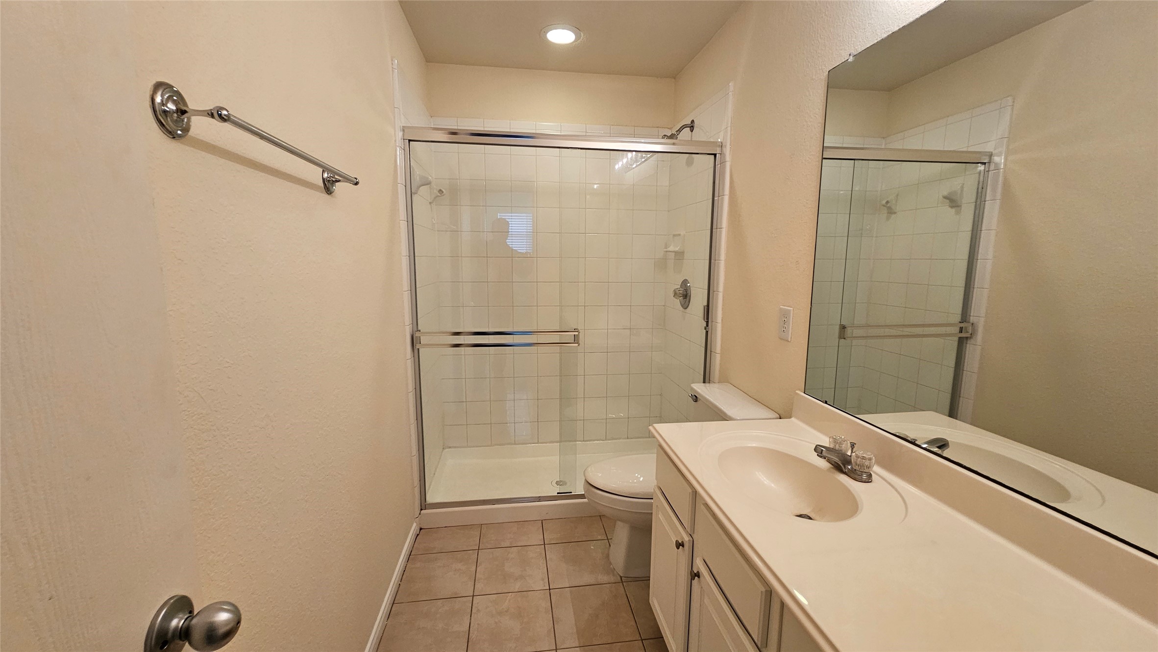 7918 Barnes Ridge Lane Houston, TX 77072 - Photo 18 of 34 This bathroom features a modern design with a glass-enclosed shower, white tile, and a single-sink vanity with ample countertop space. It also includes a large mirror and neutral-toned walls, providing a clean and spacious feel.