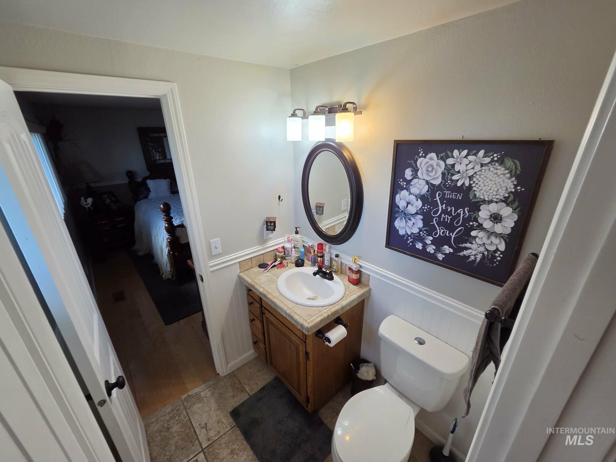 1535 Sunnyside Road Weiser, ID 83672 - Photo 16 of 26 Vanity with a round sink and a chrome faucet, wood-finish cabinetry, and a light-toned countertop