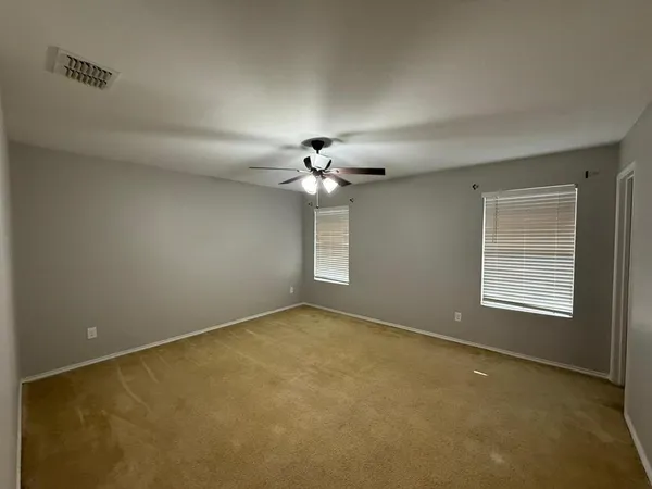 an empty room with windows and chandelier fan