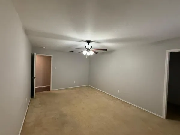an empty room with a ceiling fan and a window