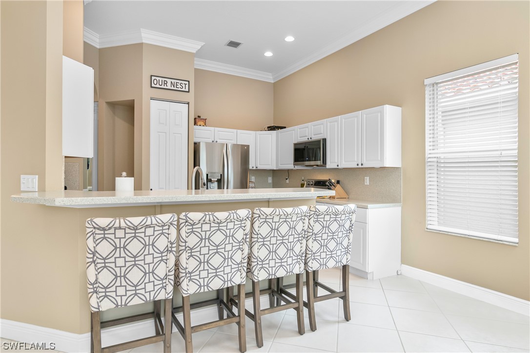 20524 Foxworth Circle Estero, FL 33928 - Photo 13 of 34 a kitchen with stainless steel appliances granite countertop a stove top oven a sink a dining table and chairs