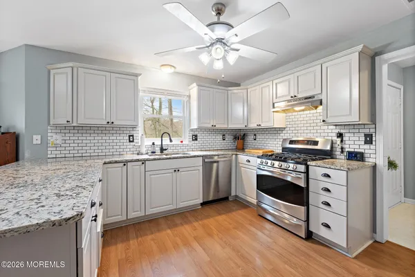 a kitchen with granite countertop a sink appliances cabinets and a counter top space