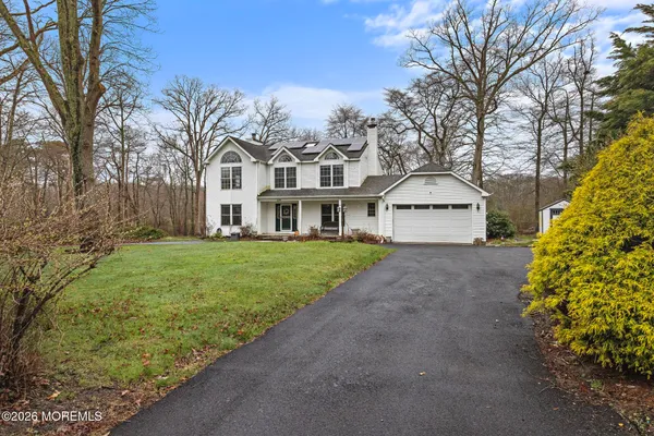 a view of a white house next to a yard with a large tree