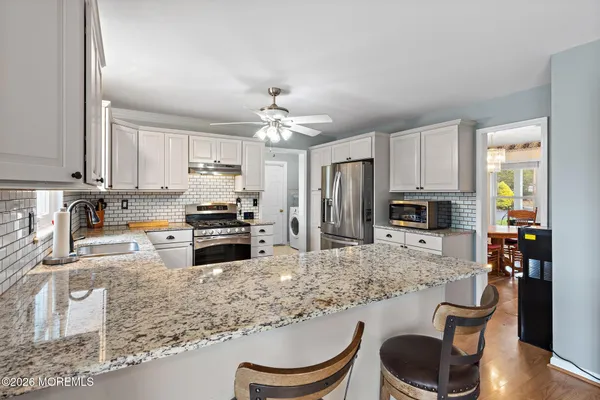 a kitchen with stainless steel appliances granite countertop a stove top oven a sink dishwasher a dining table and chairs with wooden floor