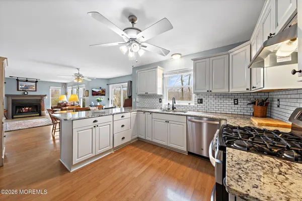 a kitchen with stainless steel appliances a sink a stove a refrigerator cabinets and living room view