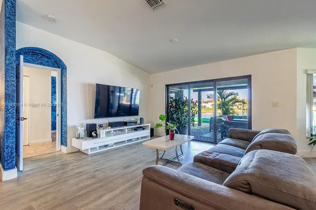 a living room with furniture kitchen view and a potted plant