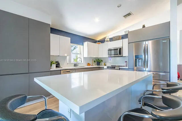 a kitchen with stainless steel appliances a sink counter space cabinets and a window