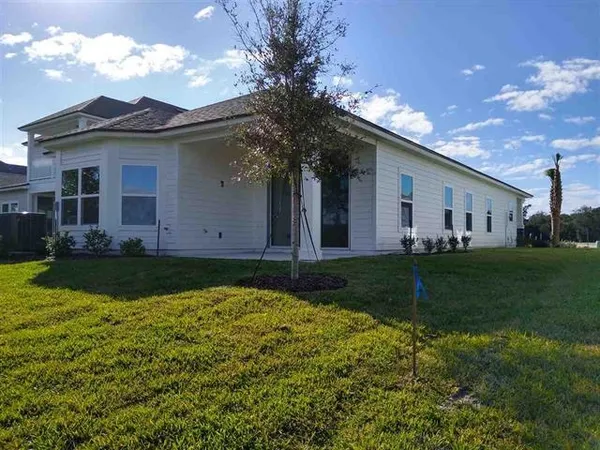 a view of a wooden house with a small yard and sitting area