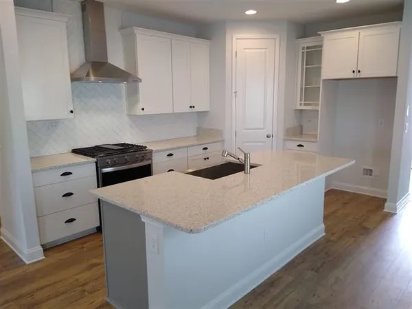 a kitchen with granite countertop a sink a stove and a refrigerator