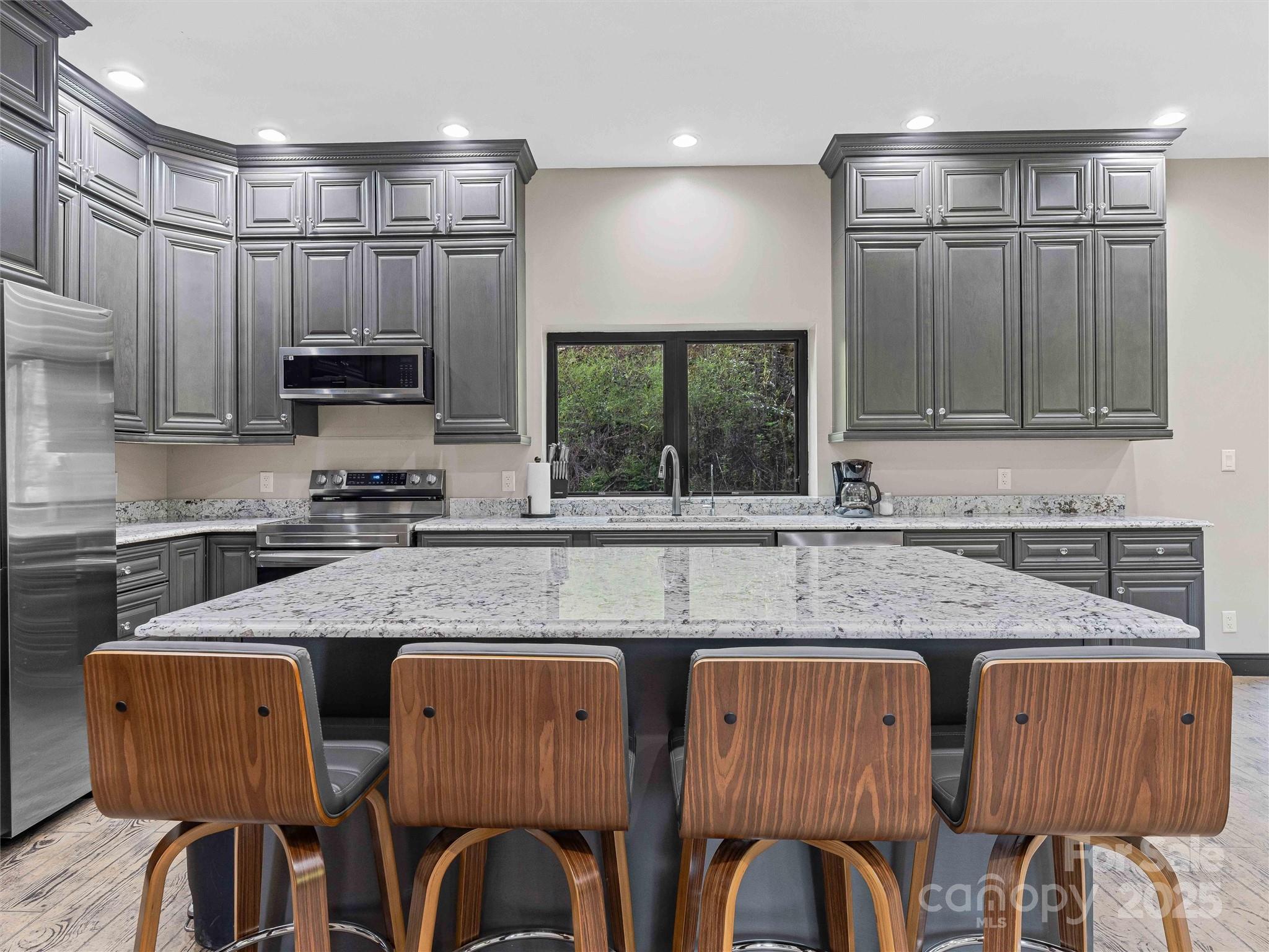 945 Roaring Fork Road Hot Springs, NC 28743 - Photo 9 of 48 a kitchen with granite countertop a table chairs microwave and cabinets
