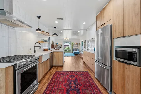 a kitchen with stainless steel appliances granite countertop a stove a sink dishwasher a refrigerator and cabinets with wooden floor