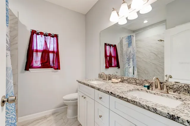 a bathroom with a granite countertop sink a toilet and a mirror