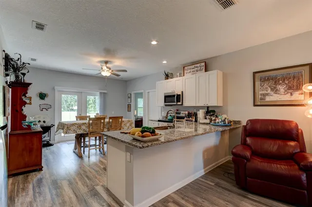a living room with furniture kitchen view and a chandelier
