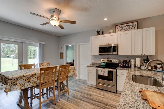 a kitchen with stainless steel appliances granite countertop a stove a sink a microwave a dining table and chairs