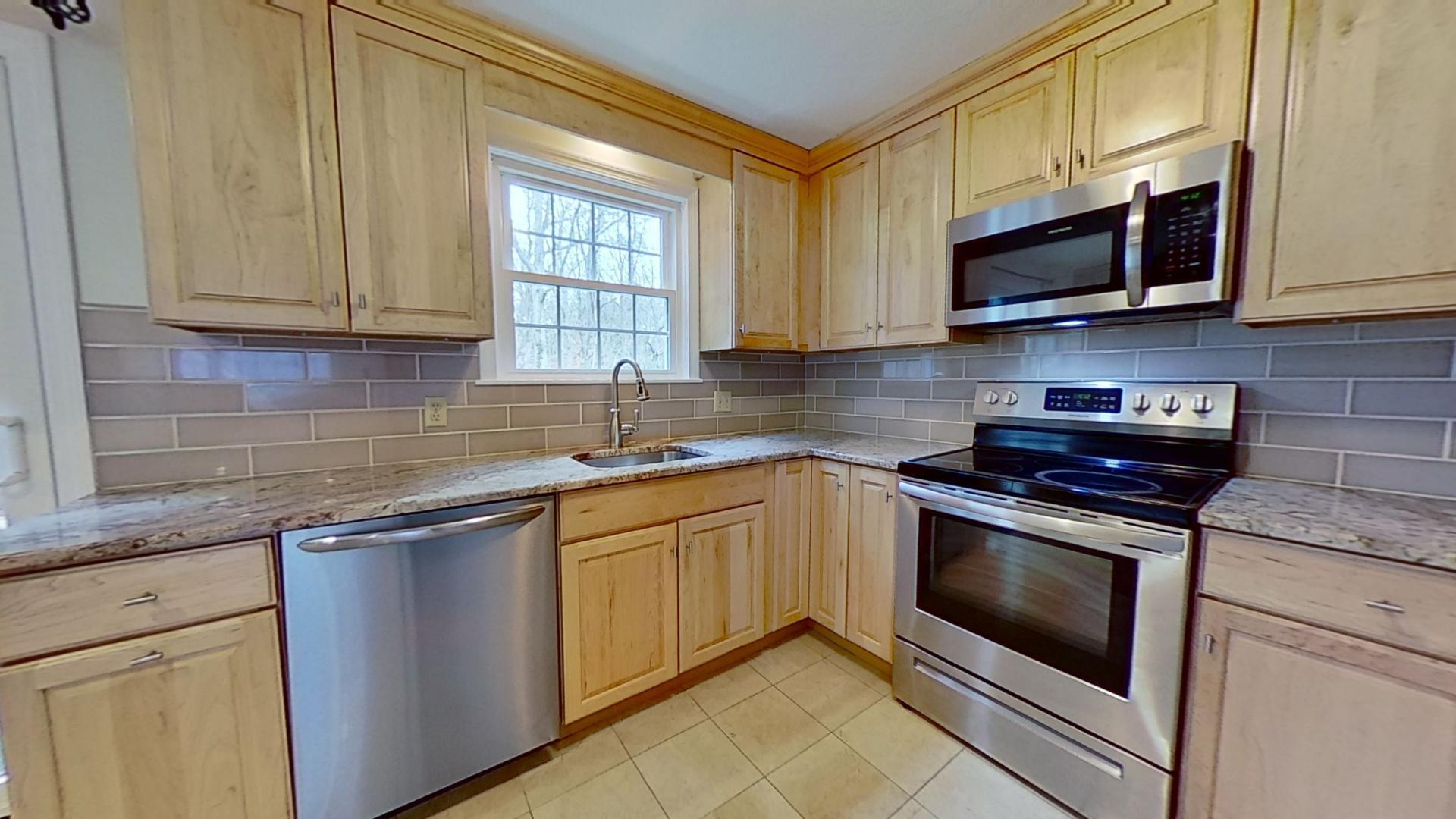 a kitchen with stainless steel appliances granite countertop white cabinets sink and a granite counter top