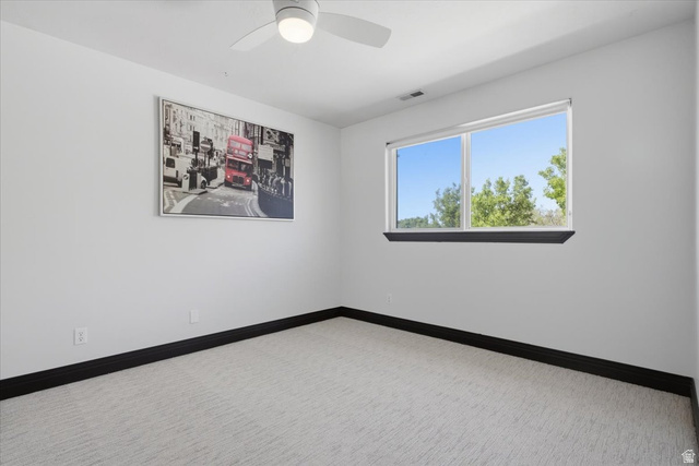 12317 Cypress Point Way Draper, UT 84020 - Photo 20 of 41 Spacious room featuring a ceiling fan, light-toned carpeting, white walls, dark baseboards, and a large window providing natural illumination