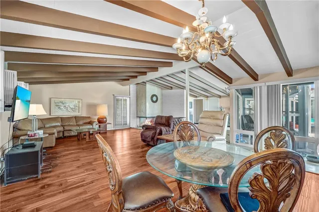 a dining room with wooden floor a chandelier a wooden table and chairs
