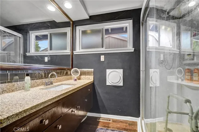 a bathroom with a granite countertop sink a mirror and shower