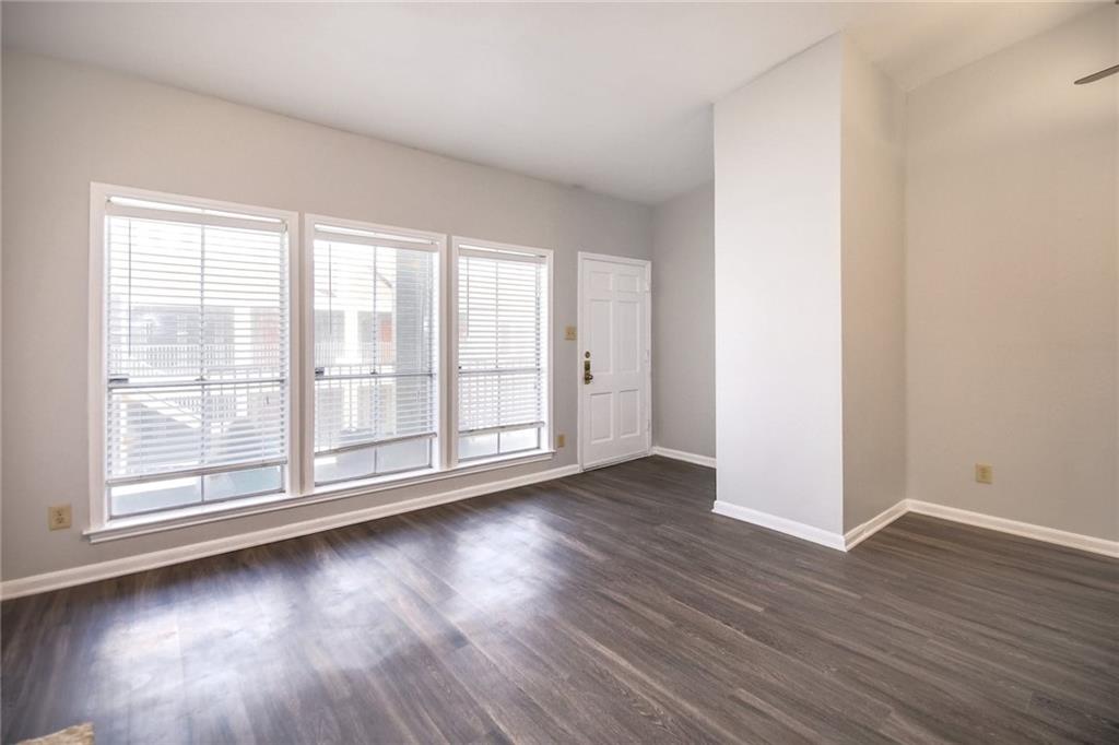 2529 Rio Grande Street, Unit 93 Austin, TX 78705 - Photo 6 of 19 Living area featuring dark wood flooring, light-colored walls, and a series of three windows fitted with blinds