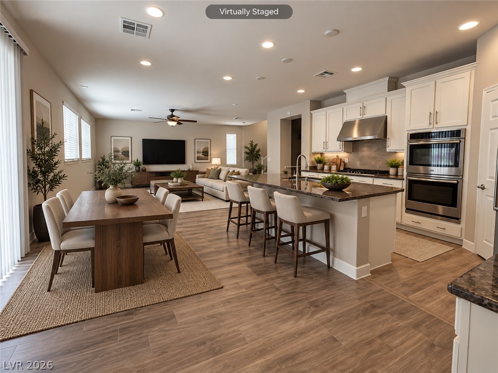 8059 Encanterra Road Las Vegas, NV 89113 - Photo 6 of 52 Gleaming wood-look floors unite the cohesive kitchen and dining zones under recessed lighting.