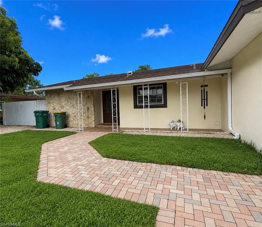 1964 42nd Street Southwest Naples, FL 34116 - Photo 3 of 25 a front view of a house with a garden and yard