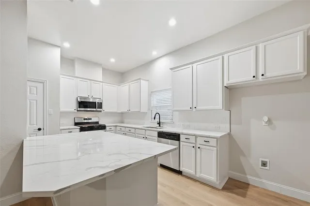 a kitchen with kitchen island a white counter top space cabinets and stainless steel appliances