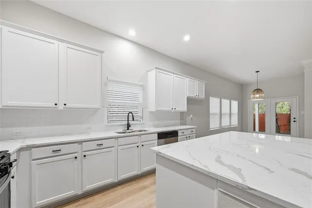 a kitchen with a sink dishwasher and white cabinets with wooden floor