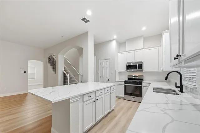 a kitchen with stainless steel appliances granite countertop a sink stove and refrigerator