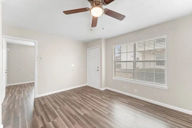 a view of a room with wooden floor and a ceiling fan