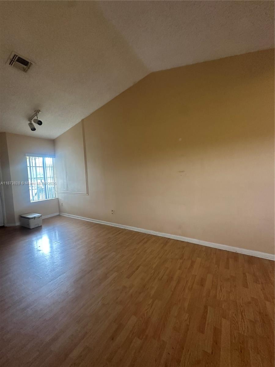 18318 Northwest 68th Avenue, Unit B Hialeah, FL 33015 - Photo 10 of 26 an empty room with wooden floor and windows