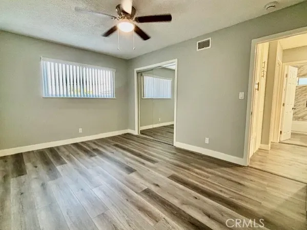 a view of empty room with wooden floor and fan