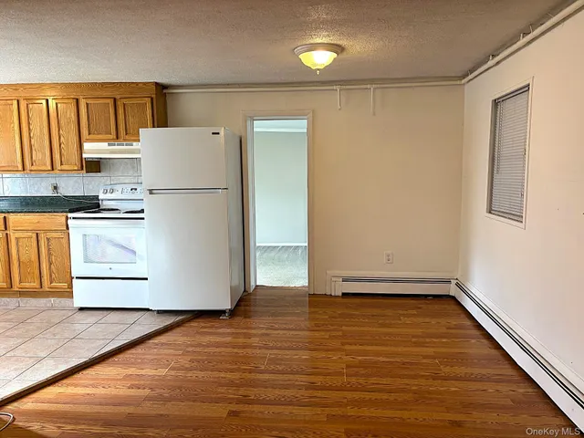 a view of kitchen with stainless steel appliances wooden floor and a refrigerator