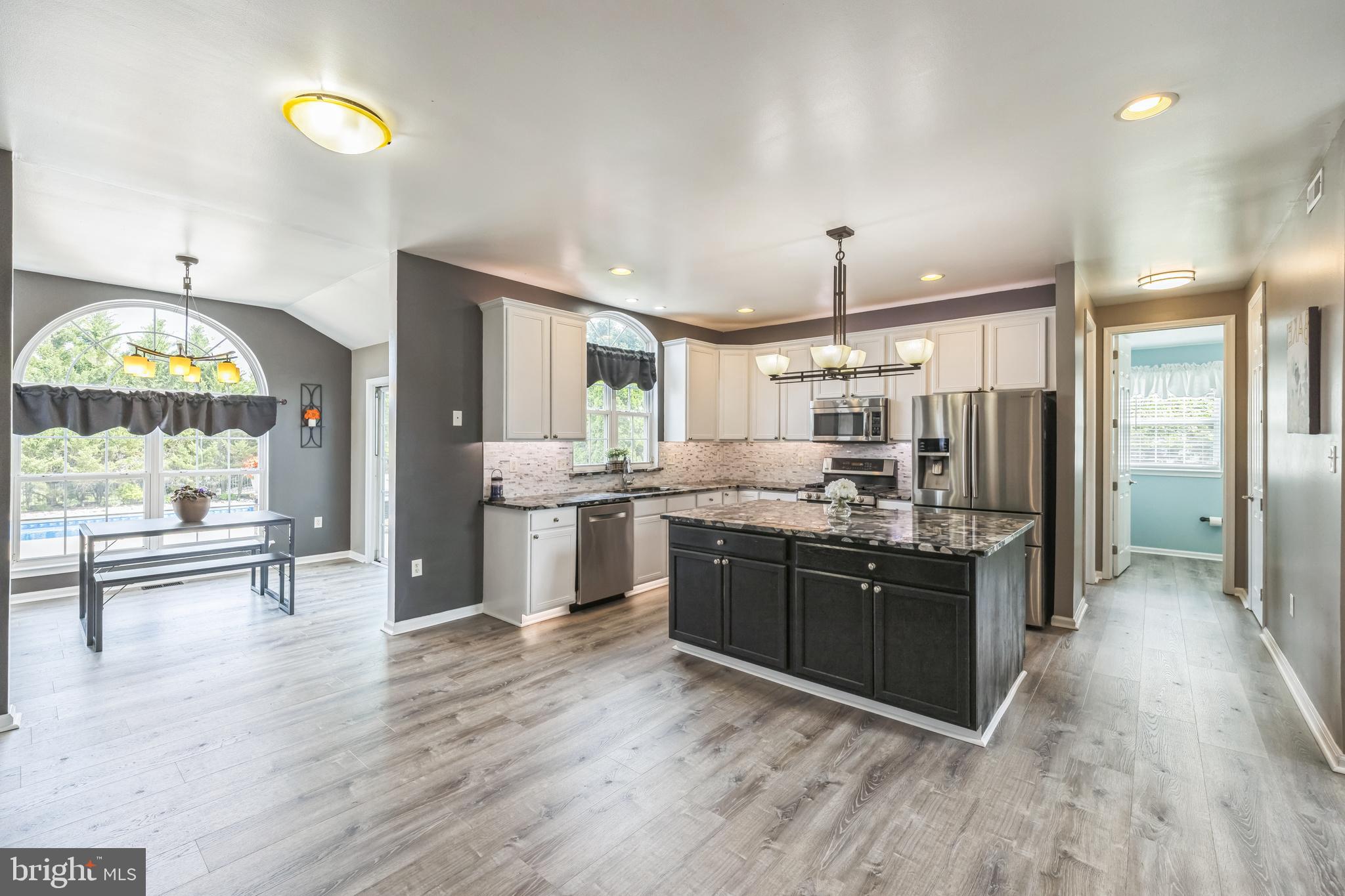 104 Abigail Lane Mickleton, NJ 08056 - Photo 28 of 75 a kitchen with stainless steel appliances granite countertop a stove a sink dishwasher a refrigerator and a dining table with wooden floor