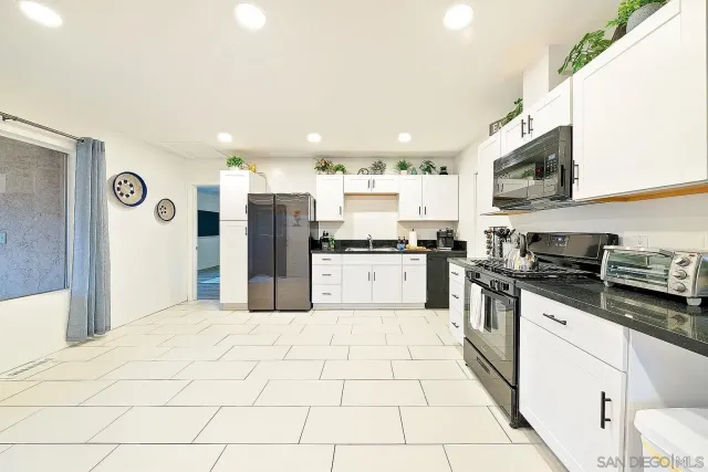 a large kitchen with stainless steel appliances kitchen island granite countertop a refrigerator and a stove top oven