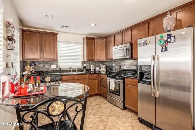 a kitchen with stainless steel appliances granite countertop a refrigerator a stove and a sink with cabinets