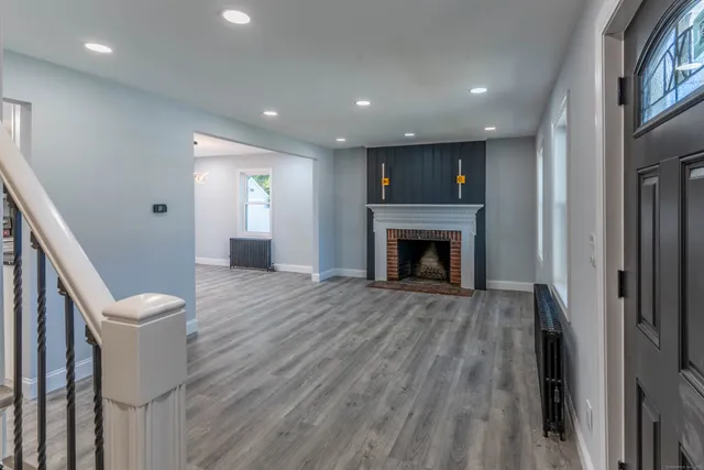 a view of an empty room with wooden floor and a fireplace