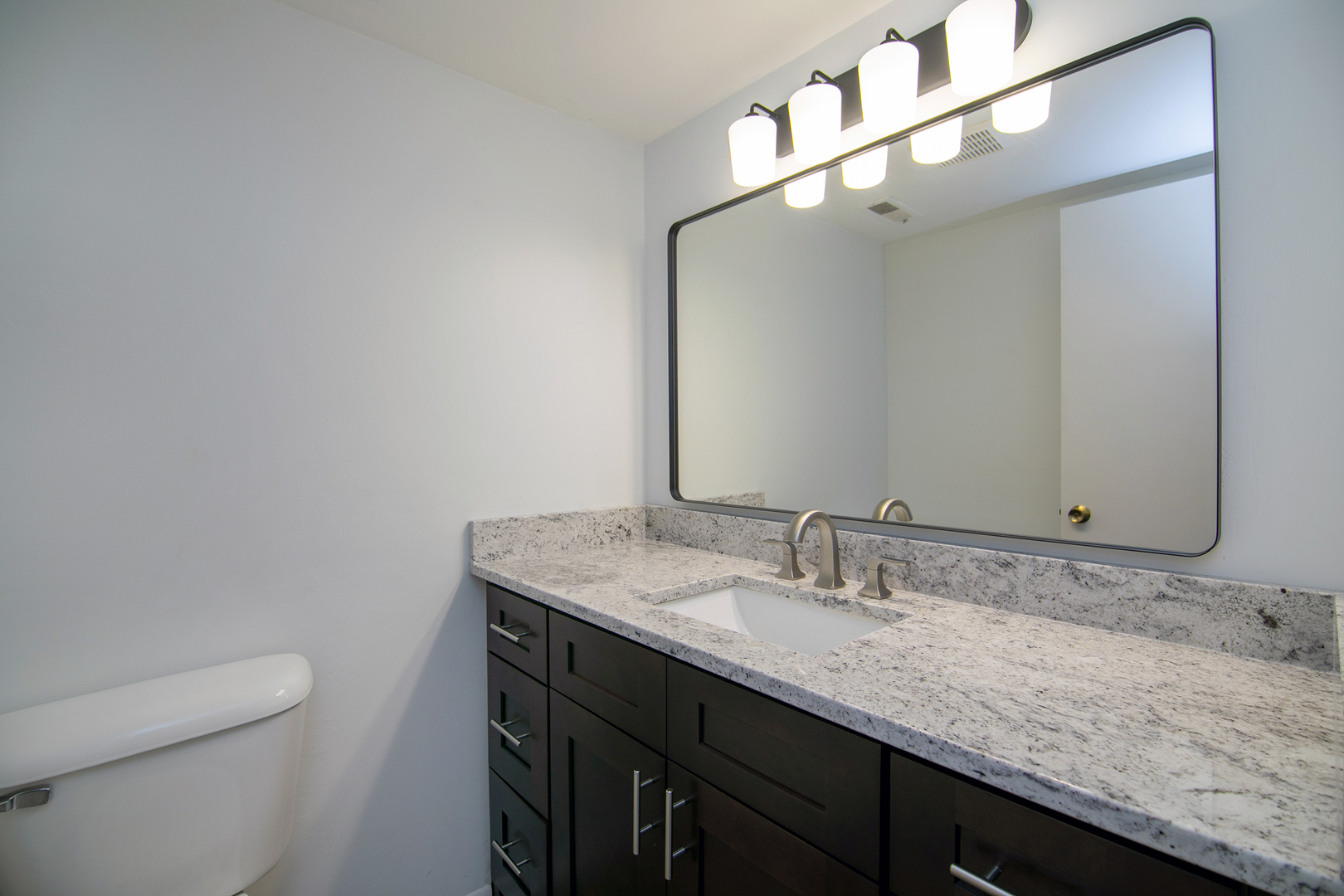 15717 Orlan Brook Drive, Unit 84 Orland Park, IL 60462 - Photo 12 of 18 a bathroom with a granite countertop sink a toilet and a mirror