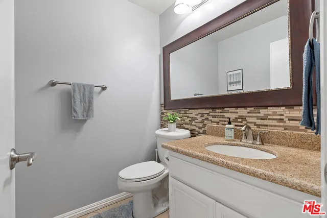 a bathroom with a granite countertop sink a toilet and mirror