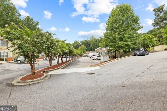a view of a white house with a fountain plants and large tree