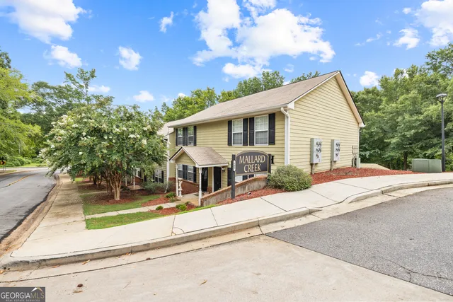 a front view of a house with a yard and potted plants