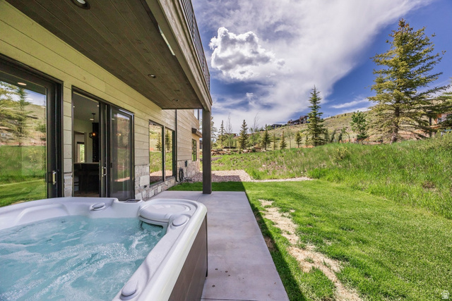140 West Vista Road Kamas, UT 84036 - Photo 49 of 101 Outdoor spa with a concrete patio, sliding glass doors, stone veneer accents, and a grassy hillside
