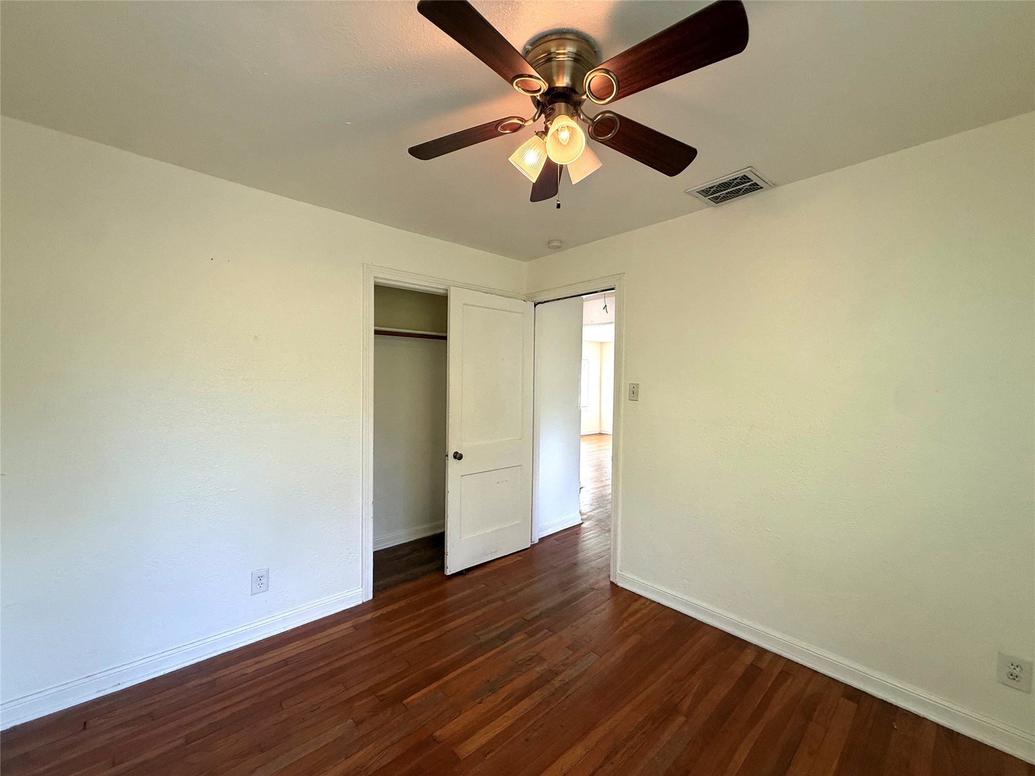 3305 Merrie Lynn Avenue Austin, TX 78722 - Photo 16 of 22 Rich hardwood flooring stretches across this comfortable bedroom, featuring a convenient closet and ceiling fan.