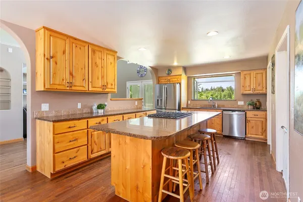 a kitchen with stainless steel appliances granite countertop a sink a stove a dining table and chairs