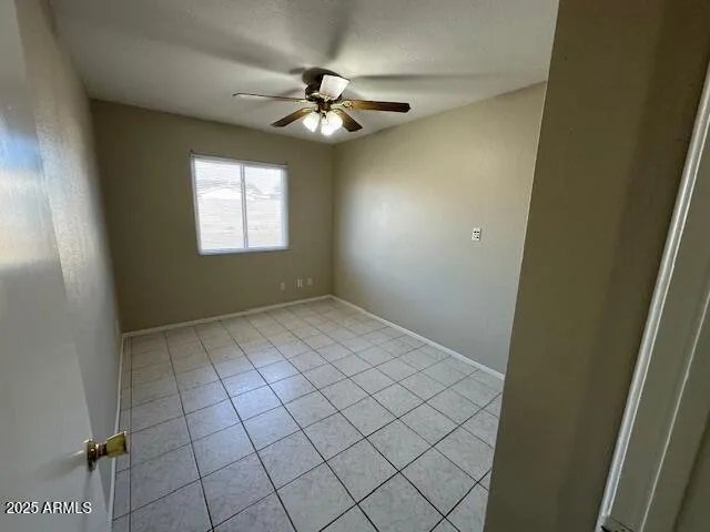 a view of an empty room and chandelier fan