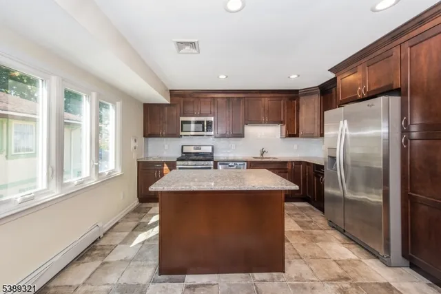 a kitchen with stainless steel appliances granite countertop a stove a sink a refrigerator and a cabinets
