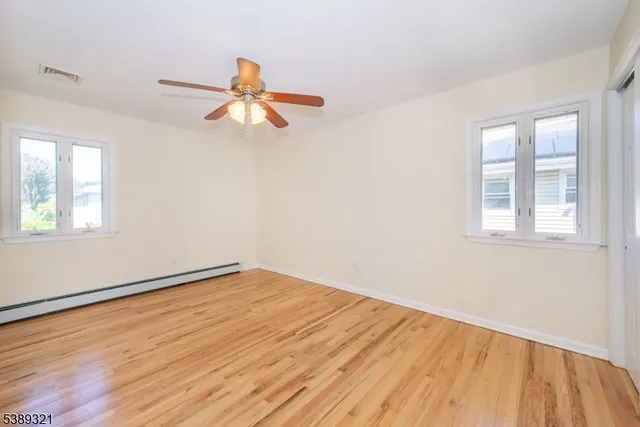 a view of empty room with wooden floor and fan
